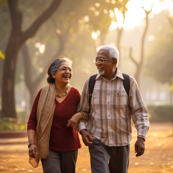 An elderly couple taking a leisurely walk hand-in-hand having a laugh at a park